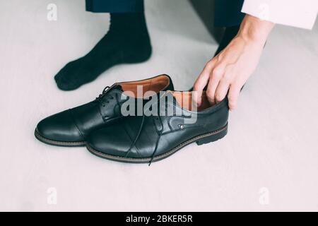 Der junge Bräutigam in einem weißen Hemd zieht schwarze Schuhe an Stockfoto