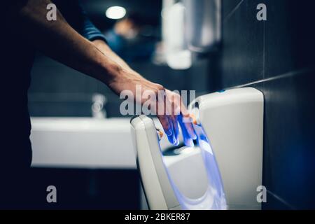 Nahaufnahme. Mann desinfiziert seine Hände im Badezimmer Stockfoto