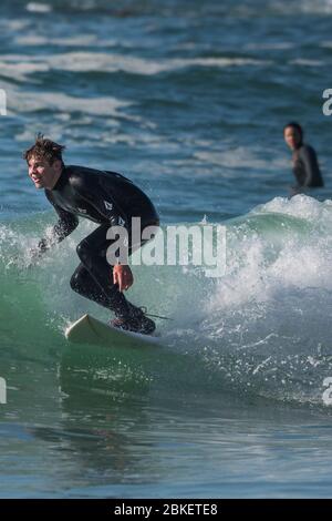 Spektakuläre Action als männlicher Surfer auf einer Welle im Fistral in Newquay in Cornwall reitet. Stockfoto