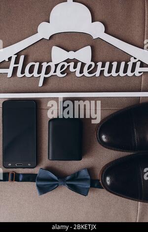 Holztrempel mit der Übersetzung 'Bräutigam' Hintergrund schwarze Schuhe, blau Schmetterling schwarz Telefon schwarz Parfüm Flasche Stockfoto