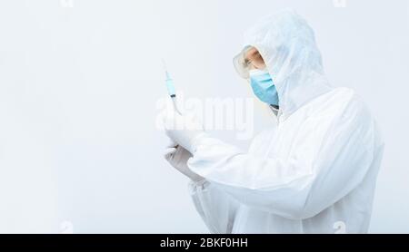 Coronavirus, Covid-19-Impfstoff. Arzt Wissenschaftler in schützenden medizinischen Anzug, biologische Gefahr, Gesichtsmaske hält Impfstoff in Spritze. Impfung Stockfoto