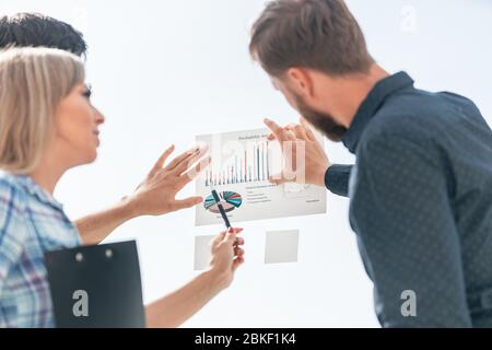 Junge Mitarbeiter zeigen auf Finanzgrafik Stockfoto