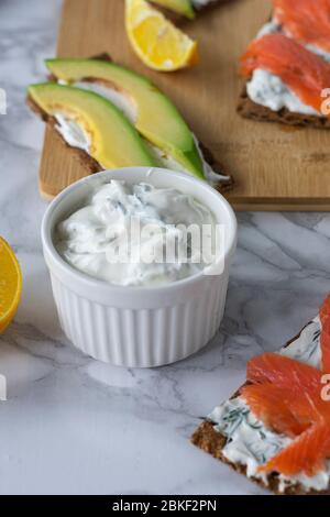 Frühstück am Morgen, zartes hausgemachtes Weichkäse auf Crackern mit geräucherter Forelle und Avocado Stockfoto