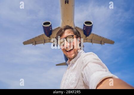 Coronavirus ist vorbei. Quarantäne geschwächt. Nehmen Sie die Maske ab. Jetzt können Sie reisen. Ein Mann macht ein Selfie gegen den Himmel und ein fliegendes Flugzeug Stockfoto