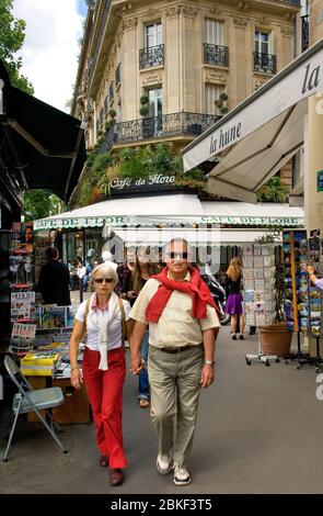 Streetscene in Paris mit einem Paar im Boulevard StGermain mit Cafe de Flore im Hintergrund und einem Papierstand links im Vordergrund, Paris Stockfoto