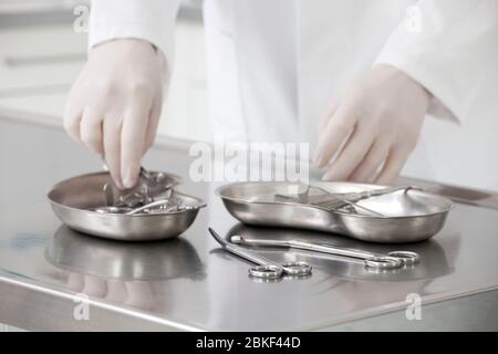 Hände einer Krankenschwester, die medizinische Instrumente nimmt - Fokus auf die Schere im Vordergrund Stockfoto