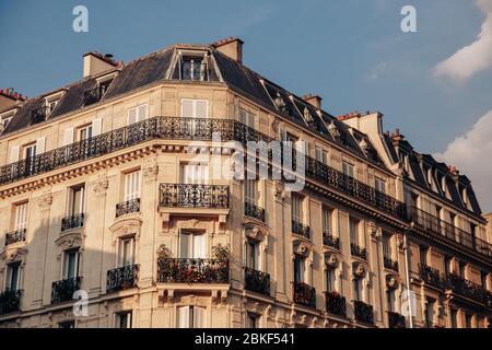 Luxus Eckhaus Dachboden Fenster mit Gitterläden, kleine Balkone und frische Blumen. Solar warm Foto Stockfoto