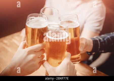 Nahaufnahme Freunde klirren Gläser mit Bier in irish Pub Stockfoto