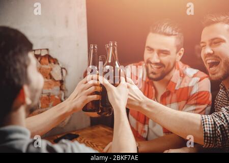 Fröhliche männliche Firma trinkt Craft Beer für Treffen an der Bar. Konzept Freizeit, Freundschaft und Feiern Stockfoto