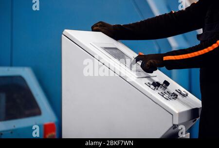 Bediener der industriellen Produktion klickt auf das Bedienfeld der automatischen Maschine. Stockfoto