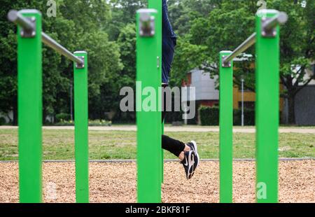 04. Mai 2020, Hessen, Frankfurt/Main: Person hat Erlaubnis ERTEILT EIN junger Mann trainiert auf einem Outdoor-Trainingsgerät im Goethepark. Die Sperre wird langsam verringert. Kinderspielplätze und Outdoor-Trainingsgeräte sind wieder geöffnet. Allerdings sind noch strenge Hygienevorschriften in Kraft und deren Einhaltung sollte überwacht werden. Foto: Andreas Arnold/dpa Stockfoto