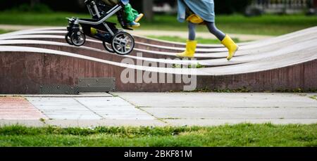 04. Mai 2020, Hessen, Frankfurt/Main: Ein Mädchen schiebt einen Kinderwagen durch den Goethepark. Die Sperre wird langsam zurückgezogen. Kinderspielplätze und Outdoor-Trainingsgeräte sind wieder geöffnet. Allerdings sind noch strenge Hygienevorschriften in Kraft, deren Einhaltung überwacht werden muss. Foto: Andreas Arnold/dpa Stockfoto