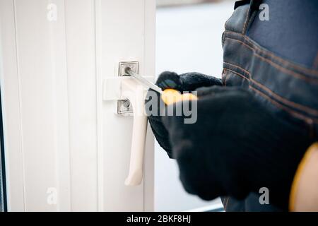 Der männliche Bauherr installiert und überprüft Kunststofffenster im Wohnhaus. Stockfoto