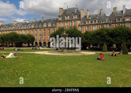 Place des Vosges mit Brunnen und Menschen in der Sommersonne entspannen, das Marais, Paris, Frankreich Stockfoto