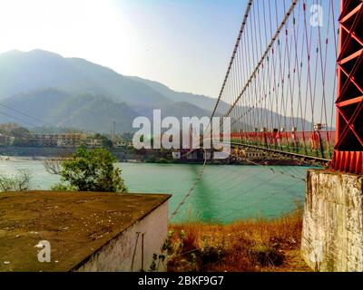 Schöne Lakshman Jhula Brücke und Ganga Fluss in der spirituellen Stadt Rishikesh, Indien Stockfoto