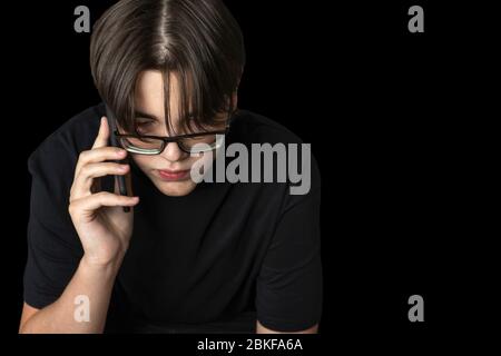 Junger Mann in der Brille reden am Telefon. Isolieren auf schwarzem Hintergrund Stockfoto