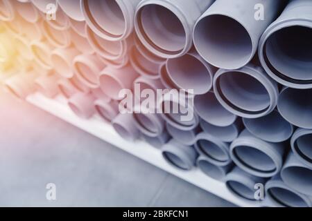 PVC-Kunststoffbauleitungen für Wasser sind in Reihe auf dem Zähler dargestellt. Hintergrund unscharf machen. Stockfoto