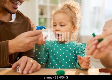 Horizontale mittlere Nahaufnahme von jungen Vater demonstriert blauen spielen Teigform zu seiner fröhlichen kleinen Tochter Stockfoto