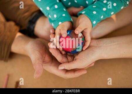 Bunte Modellierkugel in den Händen von Kind und Eltern, horizontal von oben geschossen Stockfoto