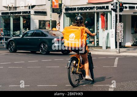 Berlin, Deutschland - 29. Juli 2019: Junge Frau auf dem Fahrrad auf der Friedrichstraße, die Lebensmittel für Lieferando, einen deutschen Lebensmittellieferdienst, liefert Stockfoto