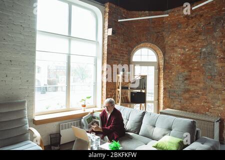 Arbeiten von zu Hause aus. Senior Mann während der Quarantäne, zu erkennen, wie wichtig zu Hause bleiben während des Virus Ausbruch. Konzept der Sperrung von Coronavirus, Selbstisolierung, Gesundheit, Sicherheit, Schutz. Stockfoto