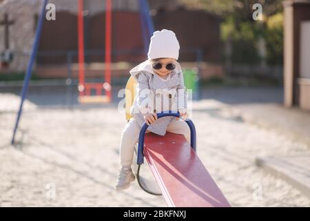 Nettes kleines Mädchen zu Fuß in Spielplatz und Spaß haben. Entzückende Mädchen in stilvollen Kleidung Stockfoto