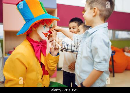 Kleiner fröhlicher Junge berührt die Nase des roten Clowns Stockfoto