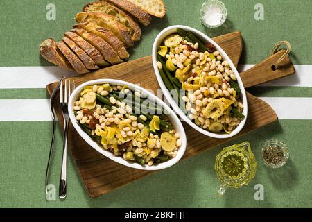 Cannellini nahrhafter weißer Bohnensalat mit grünen Bohnen, sonnengetrockneten Tomaten und Artischocken in Öl. Traditionelle italienische Küche Stockfoto