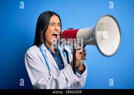 Hispanische Ärztin mit medizinischem weißen Mantel schreiend wütend auf Protest durch Megaphon. Schreien aufgeregt auf Ludspeaker reden und schreiende Nachrichten Stockfoto