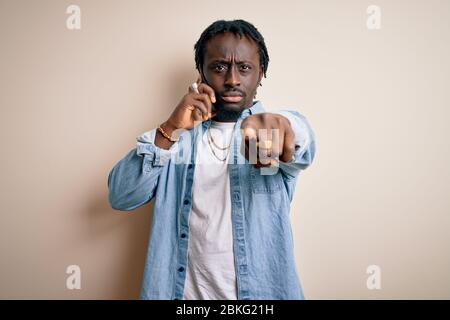 afroamerikanischer Mann mit Gespräch auf dem Smartphone über weißem Hintergrund mit Finger auf die Kamera und zu Ihnen, Handzeichen, Pos. Stockfoto