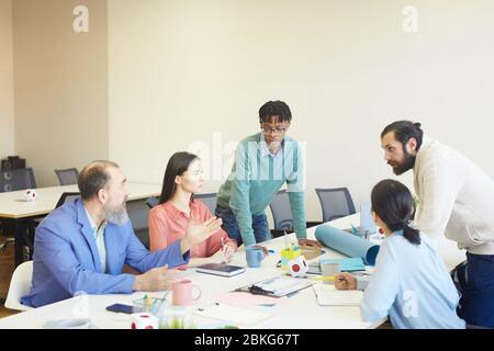 Gruppe von fünf Designern, die gemeinsam an einem neuen Projekt arbeiten und wichtige Themen diskutieren Stockfoto