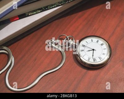 Kaukasischer Mann mit einer Taschenuhr auf klassischem Schreibtischhintergrund Stockfoto