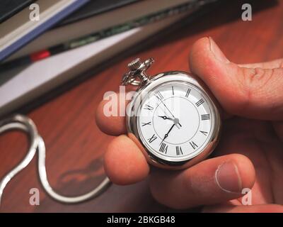 Kaukasischer Mann mit einer Taschenuhr auf klassischem Schreibtischhintergrund Stockfoto