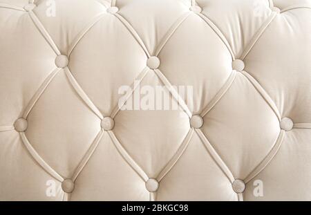 Hellbeige Velours Textil-Rautenmuster mit Knöpfen. Hintergrundkonzept. Möbel Sofa Abdeckung. Stockfoto