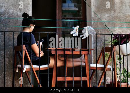 Junge Frau saß auf ihrem Balkon mit ihrem Smartphone. Stockfoto