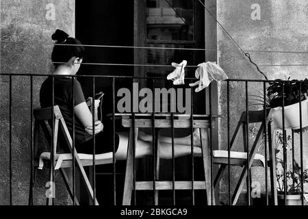 Junge Frau saß auf ihrem Balkon mit ihrem Smartphone. Stockfoto