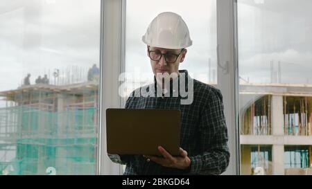 Ein schöner männlicher Ingenieur ist mit einem Notizbuch für die Arbeit. Stockfoto