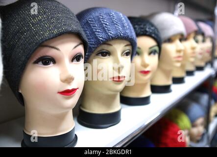 Mannequin Köpfe in gestrickten Hüte und Schals. Mannequins weibliche Köpfe in Hüten und Schals nah oben. Strickmützen und Schals aus Wolle. Weibliche Kopfbedeckung. Stockfoto