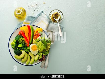 Gesundes Salatgericht mit gemischtem frischem Gemüse, Avocado und Ei auf blauem Hintergrund Draufsicht. Essen und Gesundheit. Gesundes Essen Konzept Stockfoto