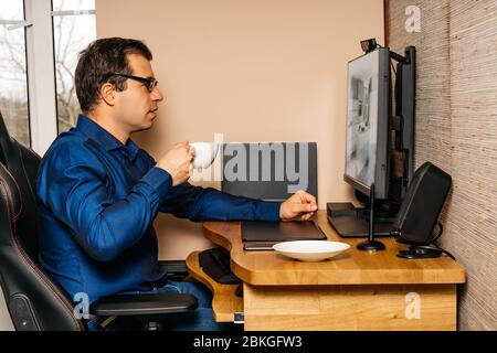 Geschäftsmann trinken Kaffee und arbeiten am Computer aus dem Komfort seines Hauses während der covid 19 oder Coronavirus Pandemien, Sperrung und Quarantäne Stockfoto
