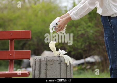 Frau wirft Plastikmüll in den Müll. Frau Hand Abholung Müllplastik für die Reinigung im Park. Müllabfuhr nach einer Pandemie. Selektiv Stockfoto
