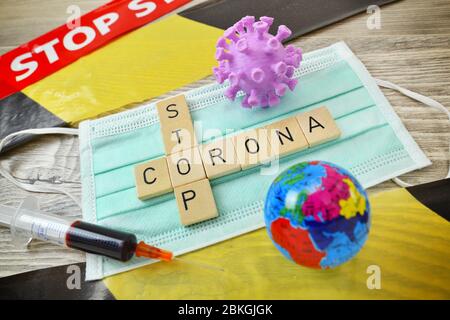 Spielbriefe bilden die Worte Corona und stoppen auf einer Schutzmaske symbolisches Foto für Maßnahmen gegen die Coronavirus Pandemie / Spielbuchgaben b Stockfoto