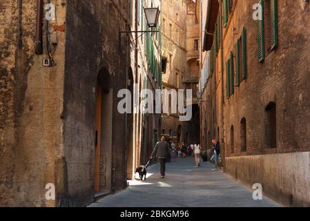 SIENA, ITALIEN 25. MAI 2017: Schöne mittelalterliche schmale Straße im Frühling. Das historische Zentrum von Siena wurde von der UNESCO zum Weltkulturerbe erklärt. Stockfoto