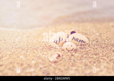 Schönes Sonnenlicht mit sauberem Meersand und die Wellen wehen am Strand. Kleine Felsen mit Inschrift, in der Nähe des Wassers. Stockfoto
