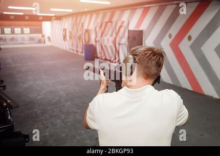 Mann schießt Pistole in Lärmschutz Kopfhörer. Schießstand Pistole. Stockfoto