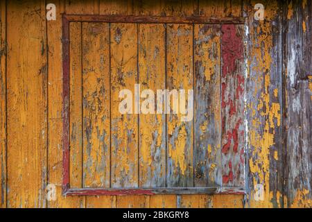 Gelbe, rote und orangefarbene Farbe auf alten Holzhauswänden Stockfoto