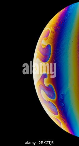 Seifenblase. Regenbogenfarben. Nahaufnahme. Schwarzer Hintergrund. Vertikal. Eine hohe Auflösung. Imitation von fantastischen Planeten. Kinderunterhaltung. Wissenschaft Stockfoto