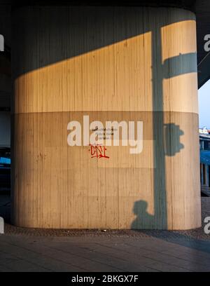 Kleben von Postern verboten. Schatten und ein einziges Grafitto auf der Autobahn-Säule in Berlin Stockfoto