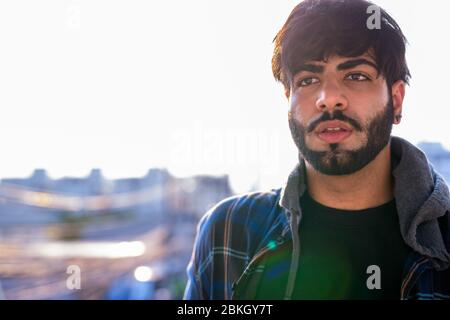 Gesicht des jungen schönen bärtigen indischen Mann gegen Ansicht der Stadt Stockfoto