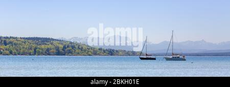 Segelboote ankern am Ammersee. Im Hintergrund Wald und einige Häuser. Die Saison für Segeln & Segeln beginnt in der Regel im April Stockfoto